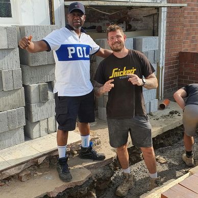 Two men posing at a construction site, smiling and relaxed.