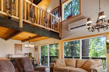 Cozy living room with large windows and wooden accents in a forest cabin.