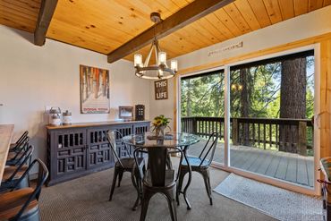 Cozy dining area with rustic decor and forest view through sliding glass doors.