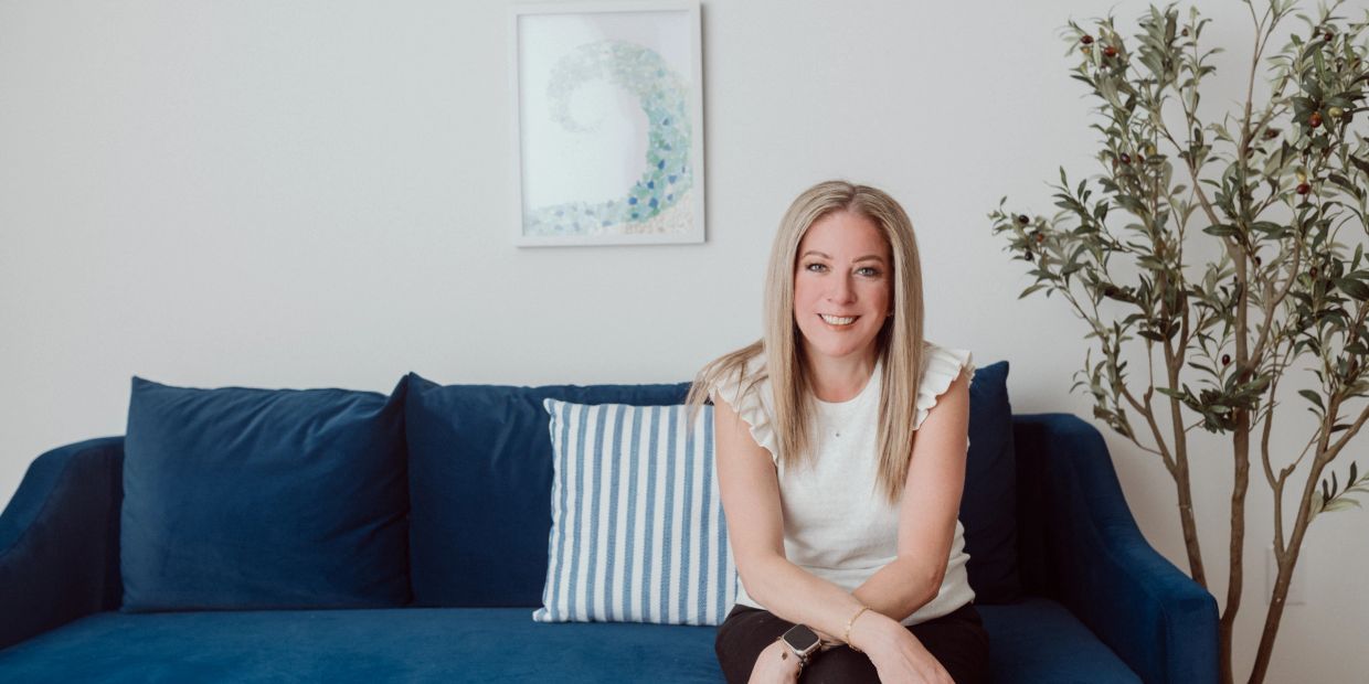 Woman sitting on a blue couch smiling.