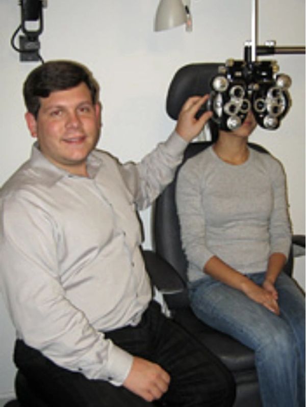 Optometrist adjusting phoropter for patient's eye exam.