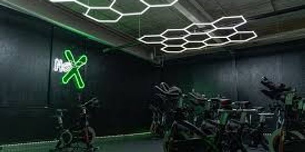 Modern indoor cycling studio with neon lights and hexagonal ceiling design.