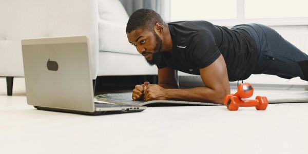 Man doing plank exercise while following a workout on his laptop.