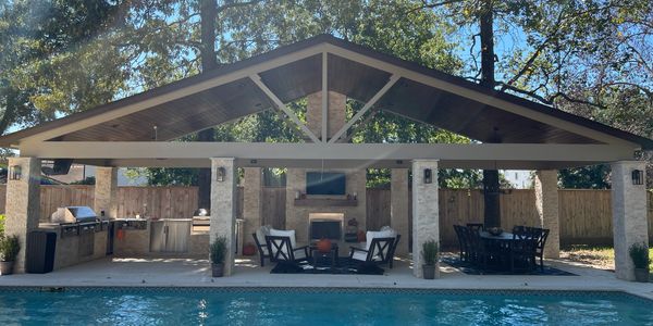 Covered outdoor patio with fireplace, seating, dining area, and pool.