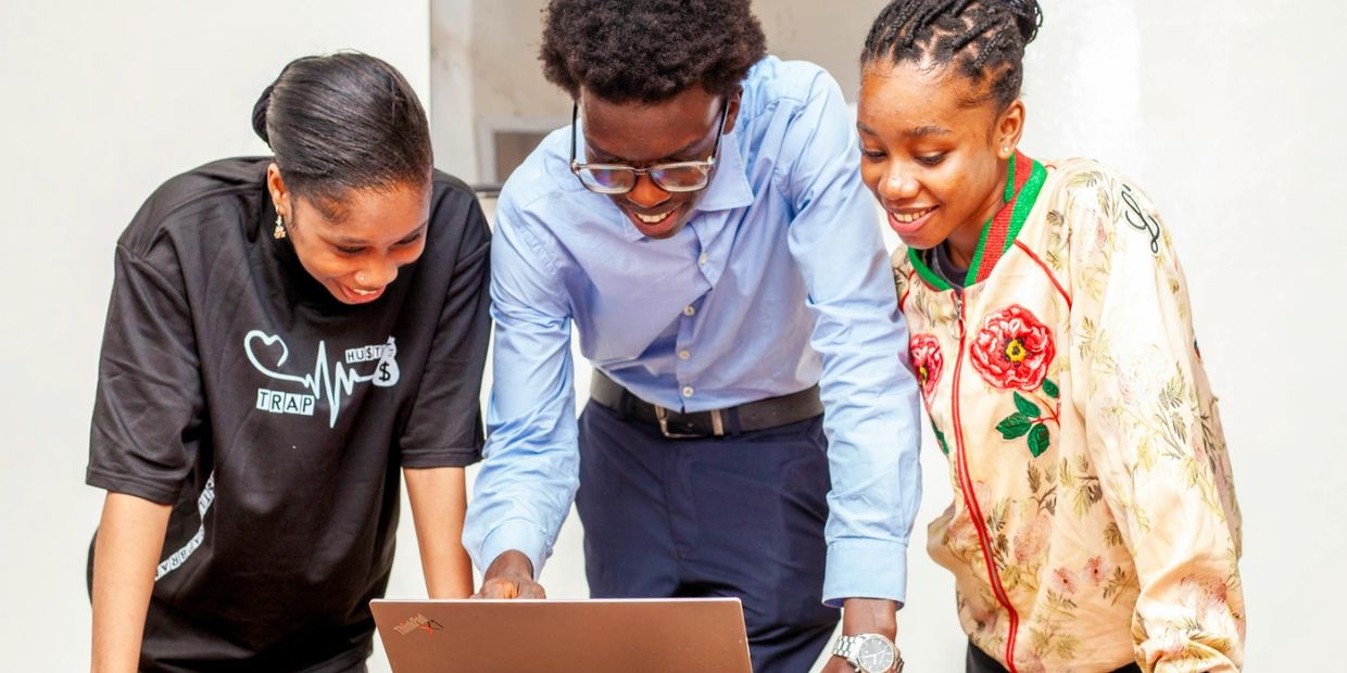 Three people happily looking at a laptop.