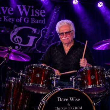 Elderly man playing drums on stage.