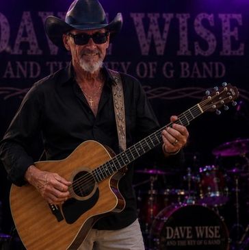 Musician playing acoustic guitar on stage.