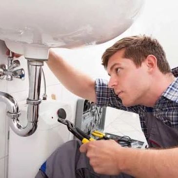 Man fixing plumbing under a sink.