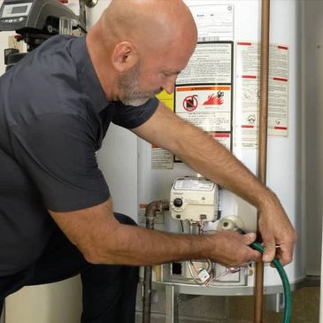 Technician working on home water heater connections.