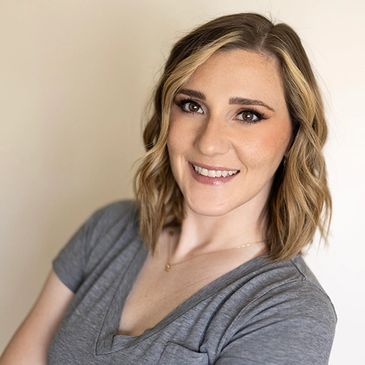 Smiling woman with wavy hair in a gray top.