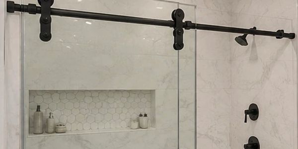 Modern bathroom shower with sliding glass door and black fixtures.