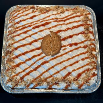Square dessert topped with whipped cream, caramel drizzle, and two cookies.