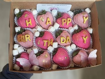 Box of pink heart-shaped cookies spelling 'HAPPY BIRTHDAY' with butterfly decorations.