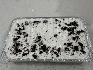 A dessert topped with crushed cookies in a foil tray.