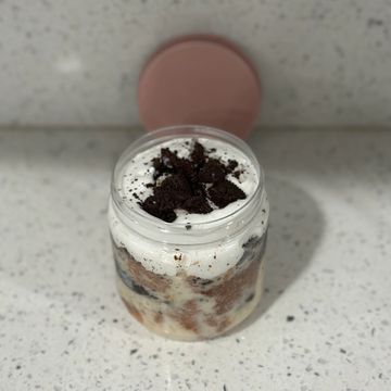 A jar dessert topped with crushed chocolate cookies and cream.