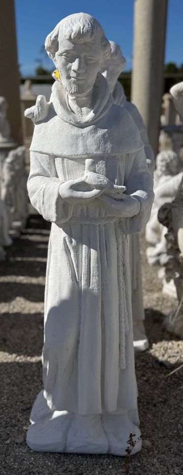 White statue of a monk holding birds with a bird on his shoulder.