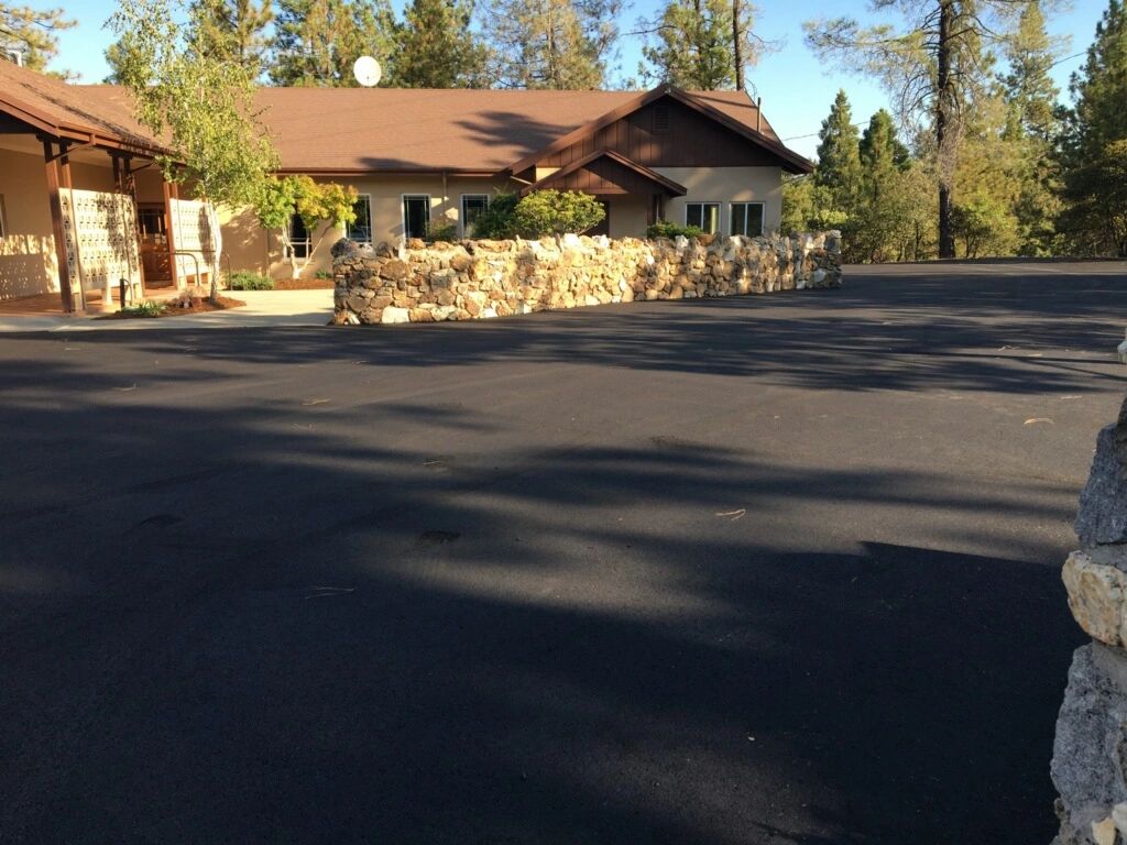 New asphalt paved church parking lot in the trees with no striping