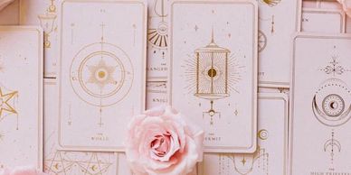 Light pink tarot cards laid out with a pink rose in the center