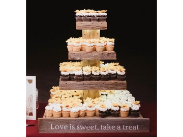 Cupcakes on a lighted wooden cupcake stand with sign Love is Sweet take a Treat