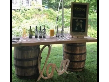 Display table with rustic wooden top and two whiskey barrels for legs with love  & blackboard sign