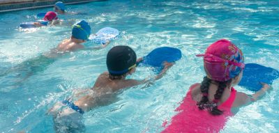 Children swimming and learning with kickboards.