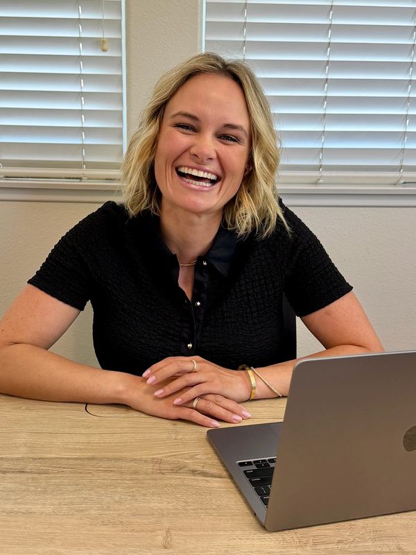 Smiling woman sitting at a desk with a laptop.