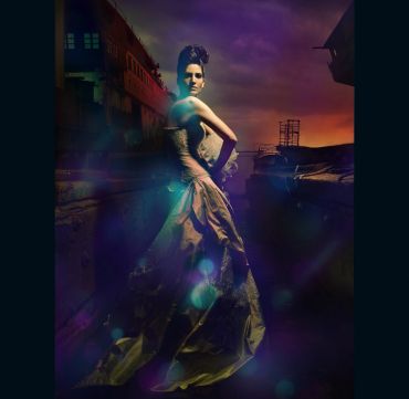 Woman in an elegant gown with a dramatic backdrop.