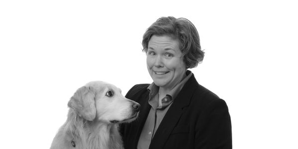 golden retriever service dog looking at a smiling woman with short hair wearing a black suit jacket