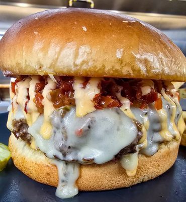 Close-up of a juicy cheeseburger with melted cheese and sauce.