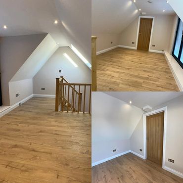 Empty attic room with wooden flooring and white walls.