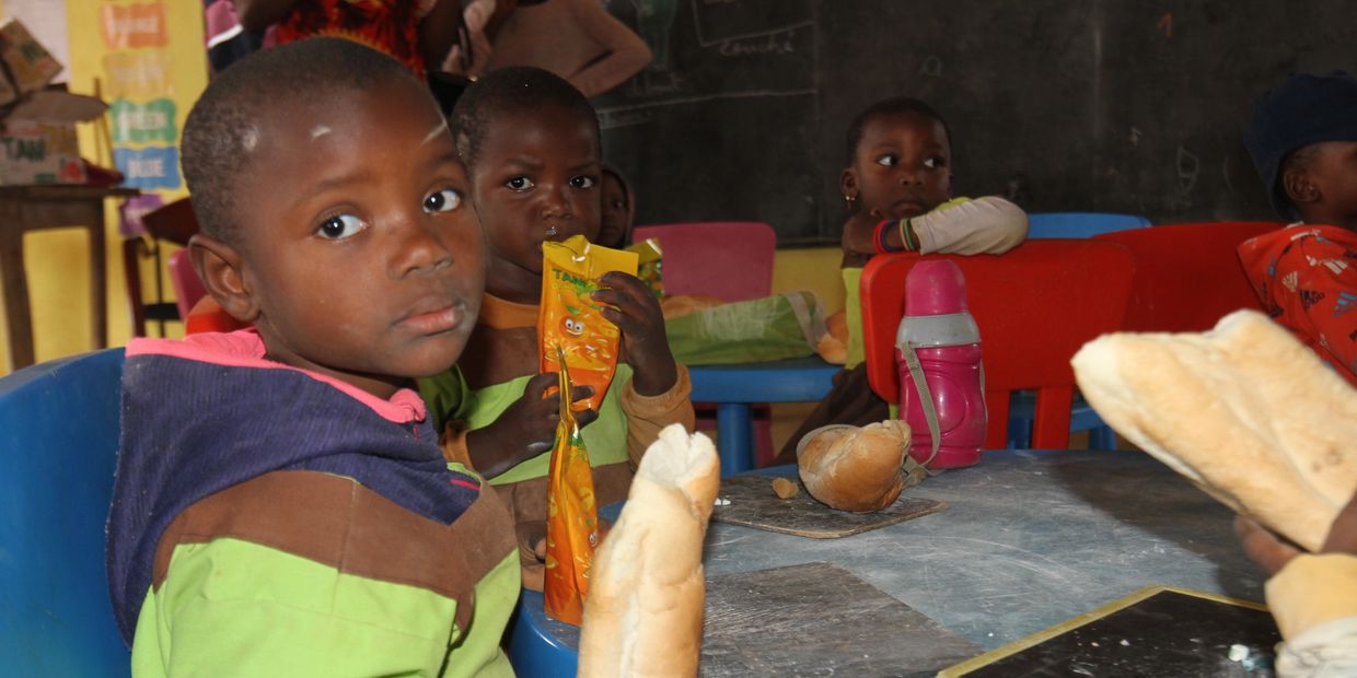 Children sitting around a table with snacks and drinks in a classroom.