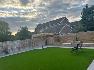 newly landscaped garden with porcelain tiles, simple pergola, sleeper beds and seating area 