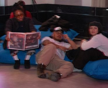 Three people relaxing on blue bean bags in a casual indoor setting.