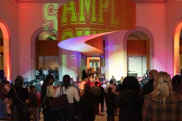Crowd gathers at an indoor event with colorful lighting and archways.