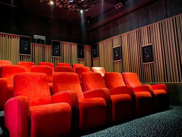 a cinema room with red chairs.