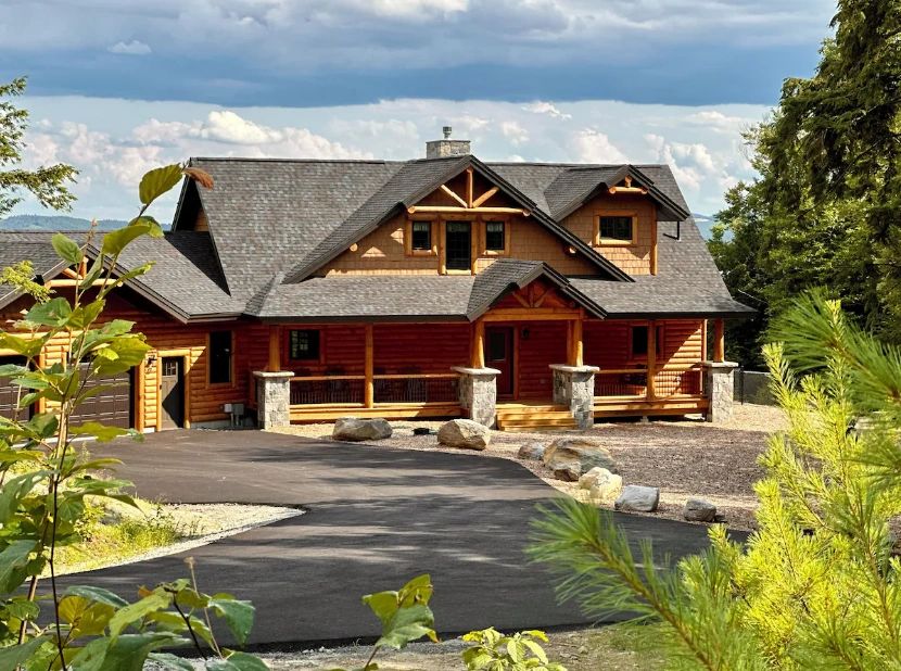 Rustic log cabin with stone accents and a curved driveway.