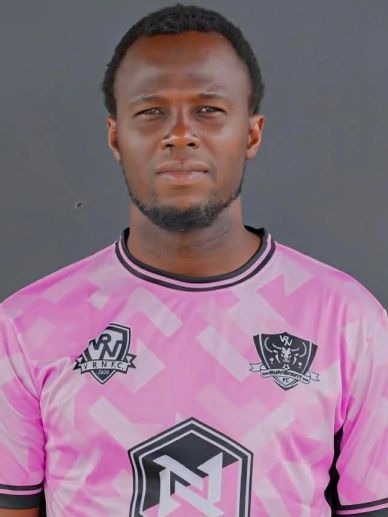 Portrait of a man in a pink sports jersey with logos.
