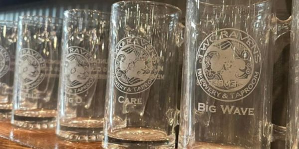 Row of empty engraved beer mugs at a brewery taproom.