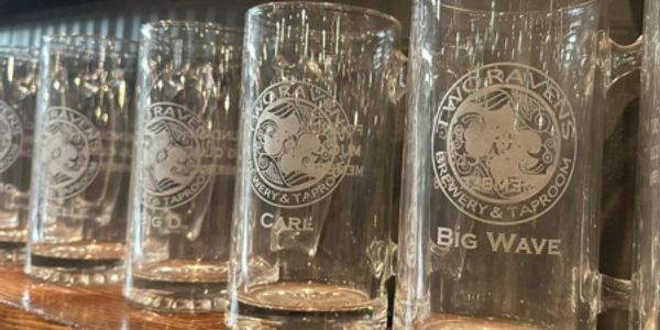 Row of empty engraved beer mugs at a brewery taproom.