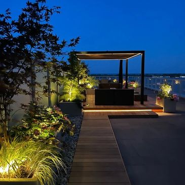 Queens Quay condo terrace with a pergola and wood deck lit up at night