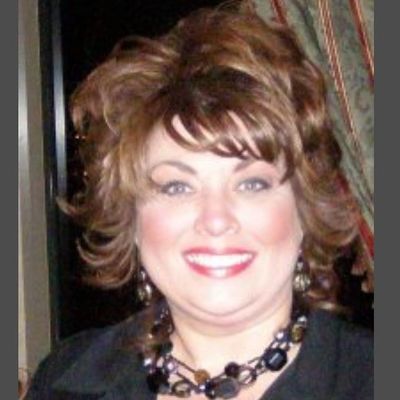 Smiling woman with short styled hair and a statement necklace.