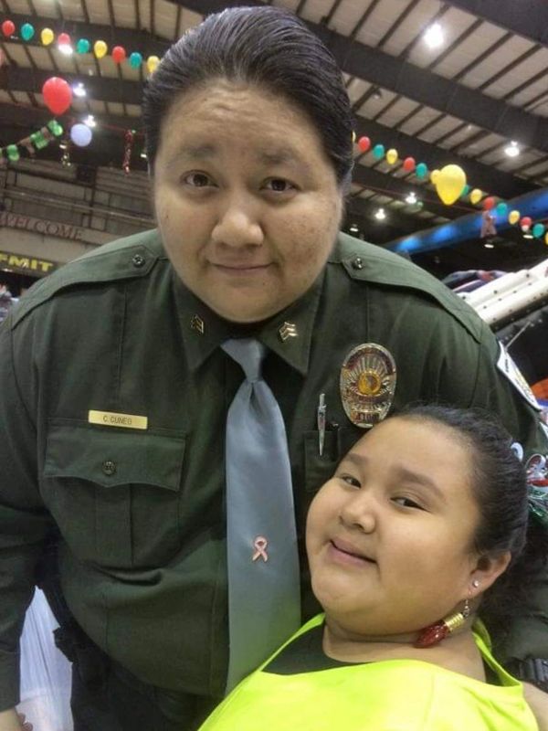 Police officer posing with a smiling child at a festive event.