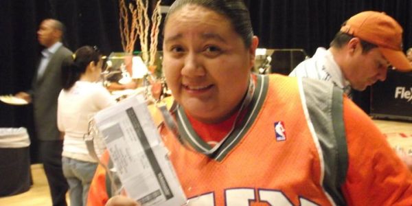 Person smiling and holding a ticket indoors.