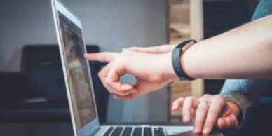Deux personnes pointent un écran d'ordinateur portable.