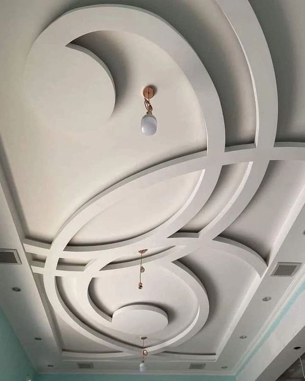 Modern ceiling design with circular patterns and hanging light bulbs.