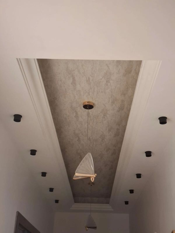 Modern ceiling design with recessed lighting and unique pendant lights.