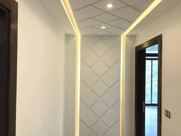 Modern hallway with geometric wall design and recessed lighting.