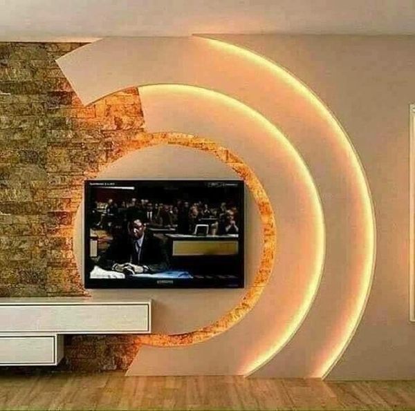Modern TV wall design with circular stone and light accents.