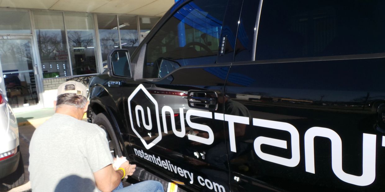 Man working on a black truck with 'nstanu' logo.