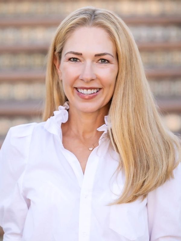 Smiling woman with long blonde hair in a white blouse.